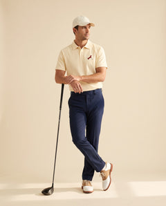 Man wearing Putting dachshund golf polo, full-body studio look. Color: Apricot