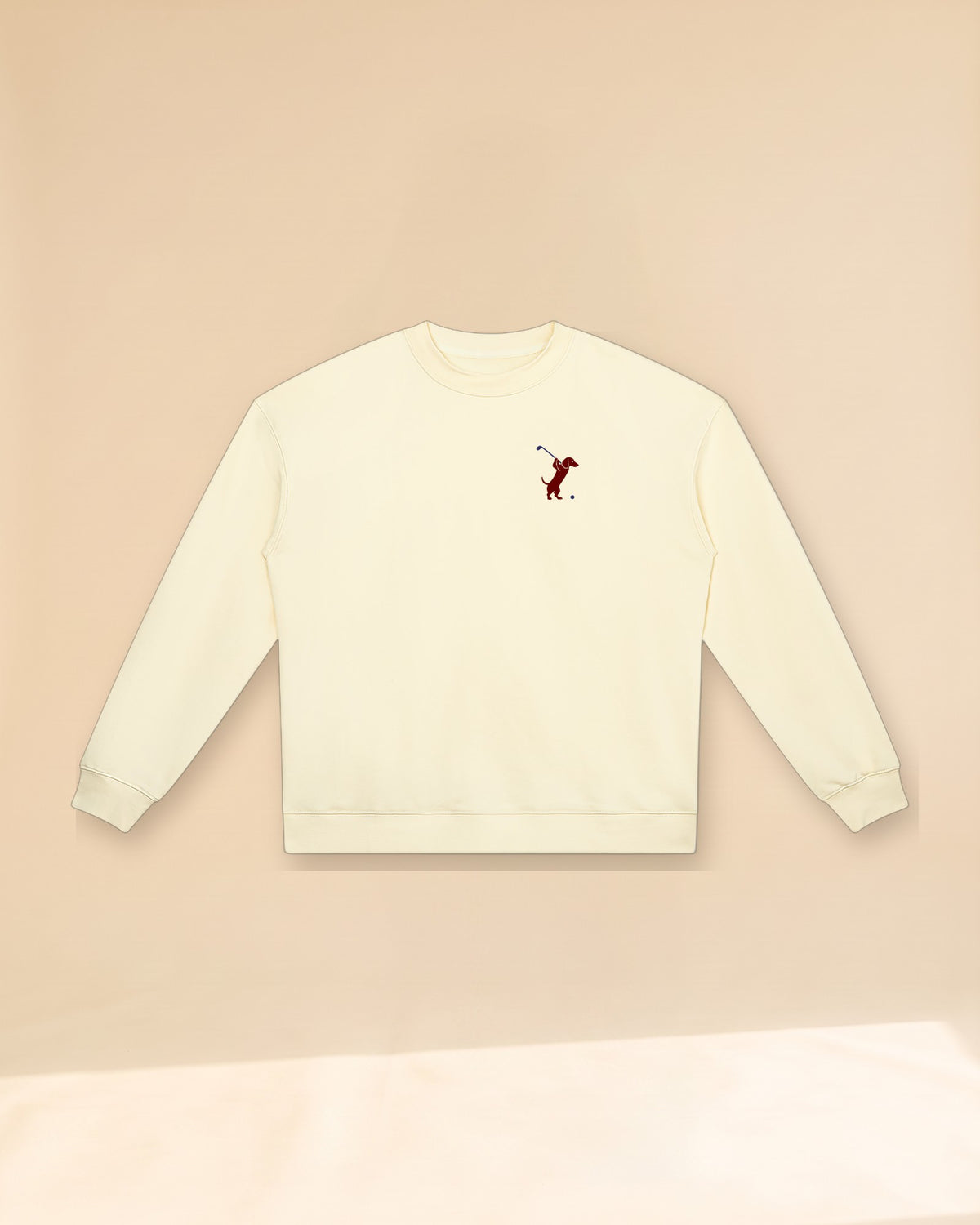 Swing dachshund golf sweatshirt, front flatlay. Color: Apricot
