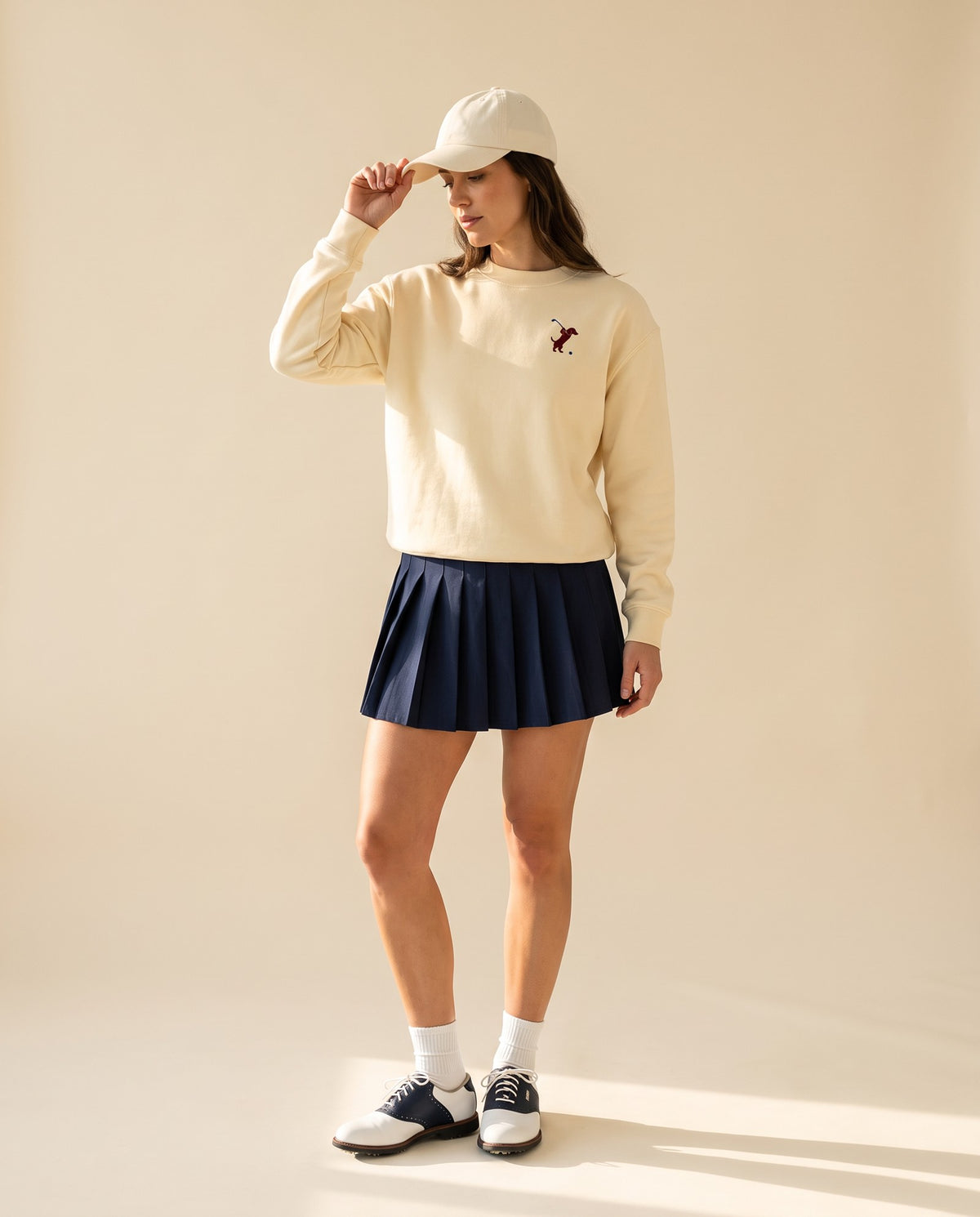 Woman wearing Swing dachshund golf sweatshirt, full-body studio look. Color: Apricot