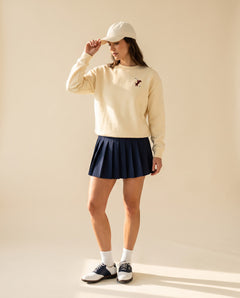 Woman wearing Swing dachshund golf sweatshirt, full-body studio look. Color: Apricot