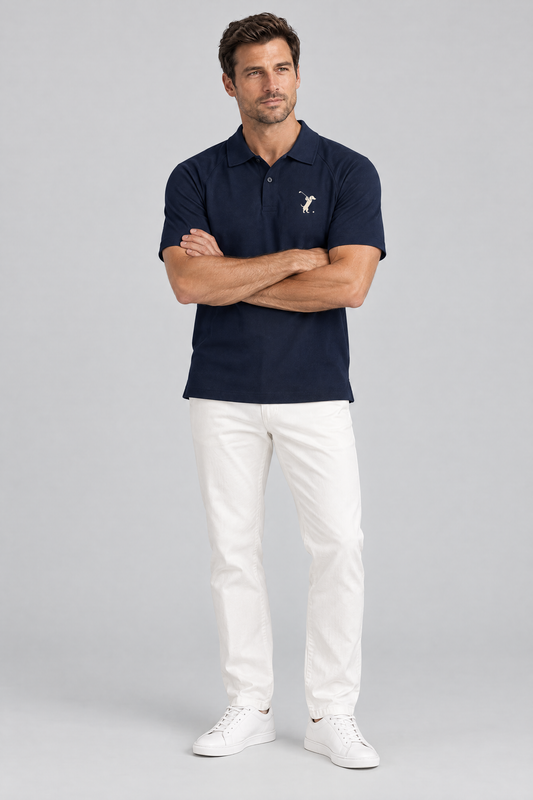 Man with crossed arms in the navy blue Swing dachshund golf polo and white trousers. Color: Navy Blue
