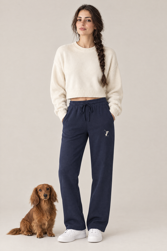Woman standing with a long-haired dachshund at her feet in navy blue Swing dachshund golf sweatpants and a cream cropped sweater. Color: Navy Blue