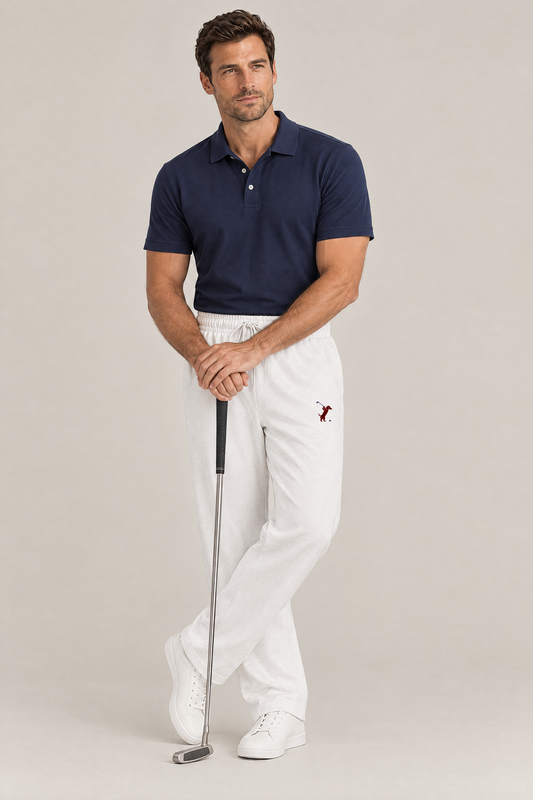 Man leaning with both hands on a putter in white Swing dachshund golf sweatpants and a navy polo. Color: White