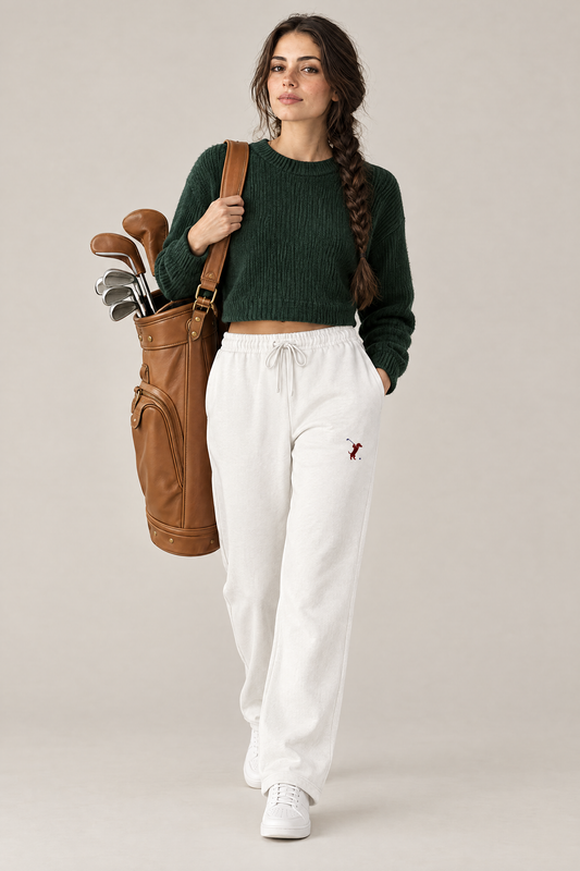 Woman walking with a tan leather golf bag in white Swing dachshund golf sweatpants and a dark green cropped sweater. Color: White