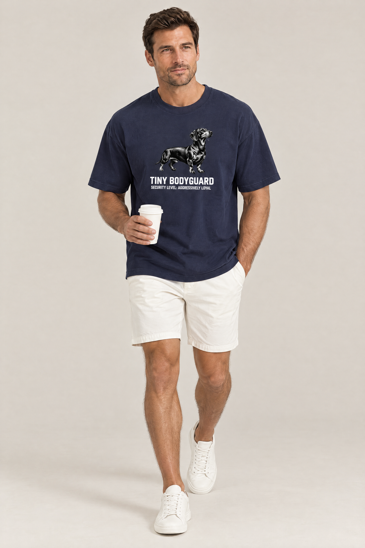 Man walking with a coffee cup in the navy Tiny Bodyguard Dachshund Tee. Color: Navy