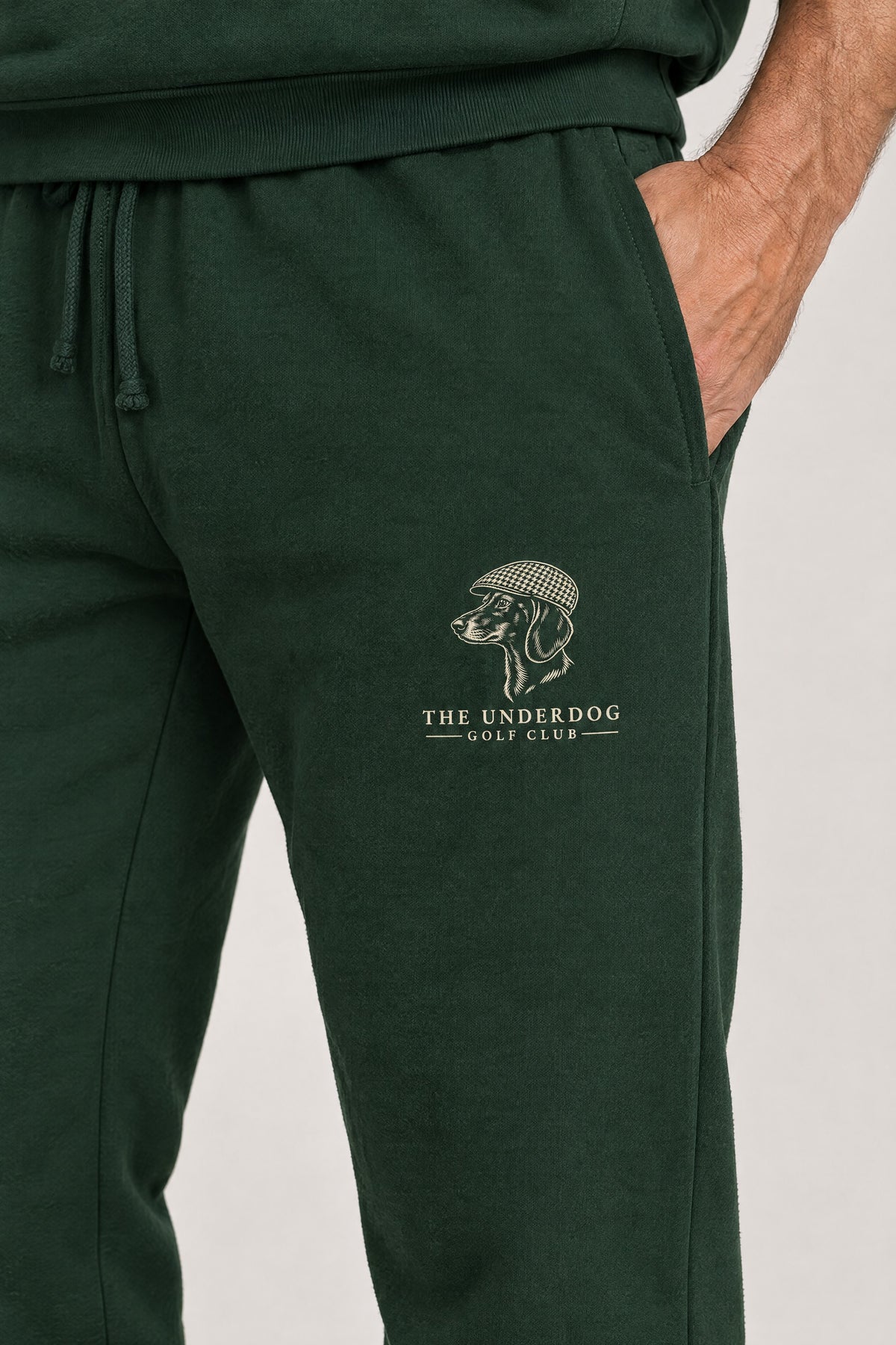 Close-up of The Underdog Golf Club dachshund crest on the left thigh of the Blackish Green sweatpants. Color: Blackish Green