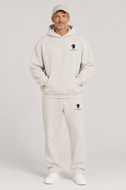 Man wearing The Long Drive dachshund golf hoodie and matching Underdog Golf Club sweatpants in Oat Gray, front view. Color: Oat Gray