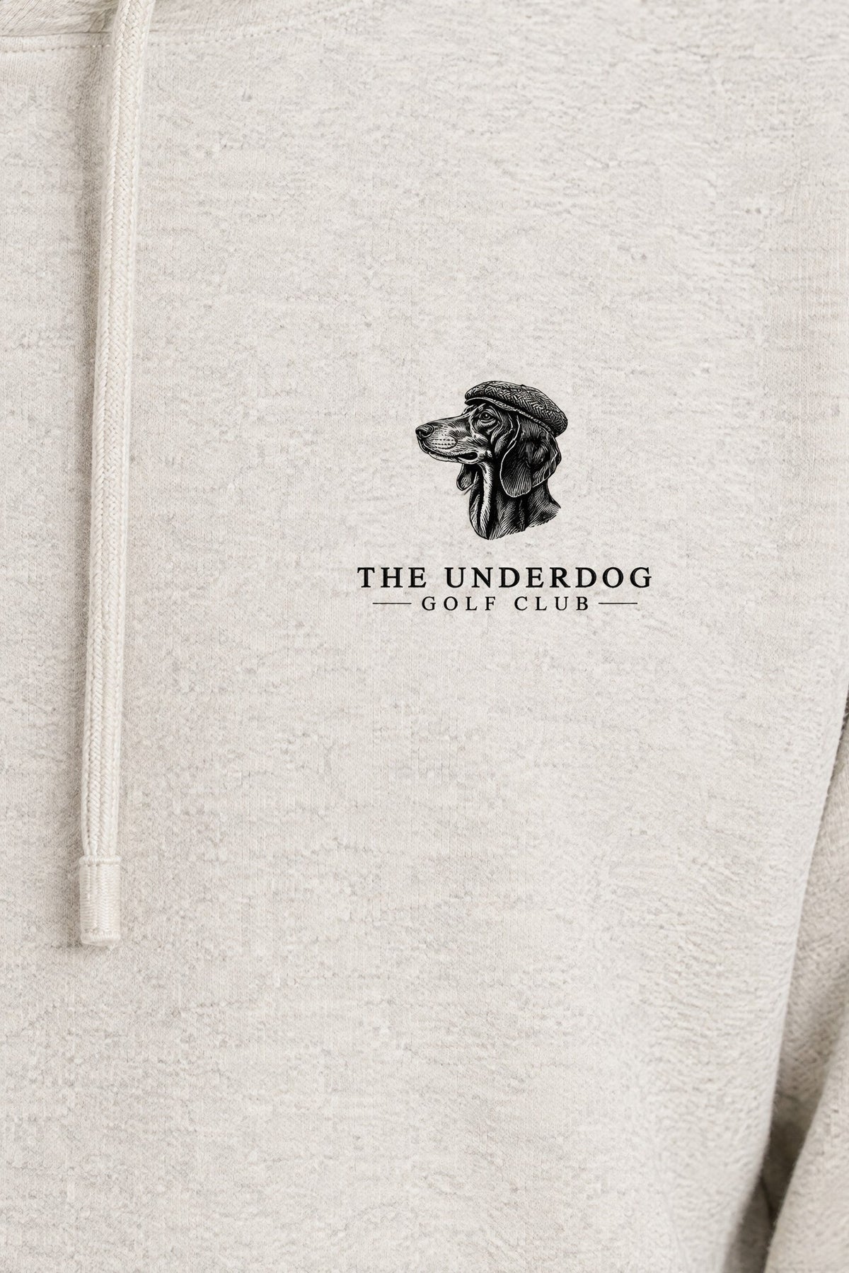 Close-up of The Underdog Golf Club dachshund crest printed on the left chest of the Oat Gray hoodie. Color: Oat Gray