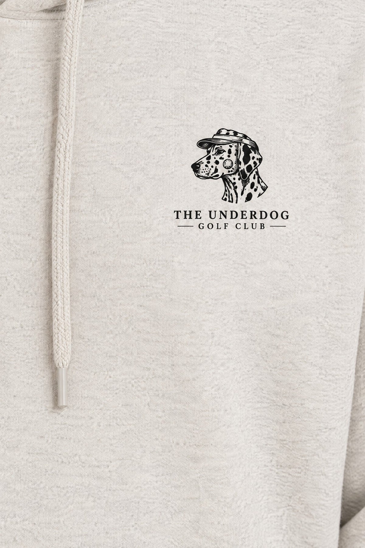 Close-up of The Underdog Golf Club Dalmatian crest printed on the left chest of the Oat Gray hoodie. Color: Oat Gray