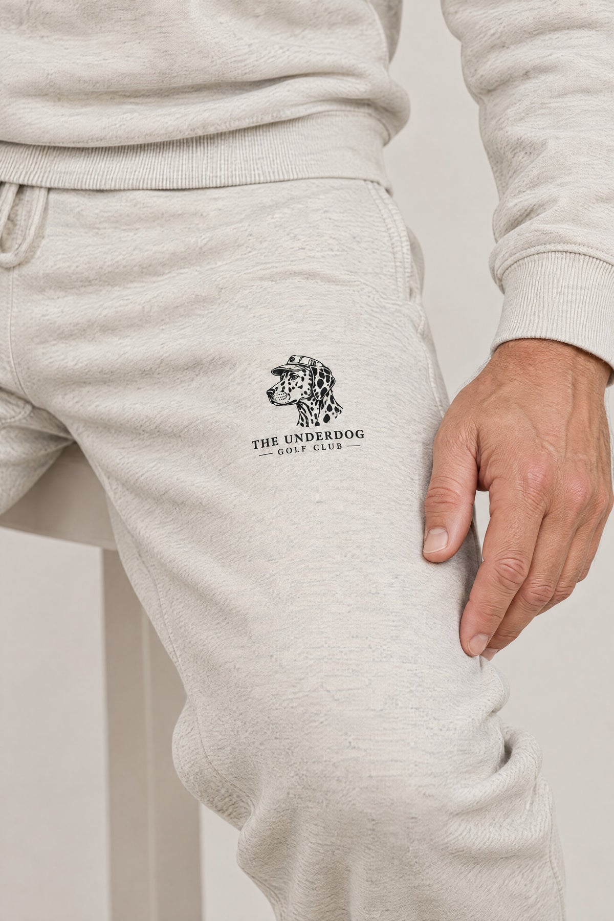 Close-up of The Underdog Golf Club Dalmatian crest on the left thigh of the Oat Gray sweatpants. Color: Oat Gray