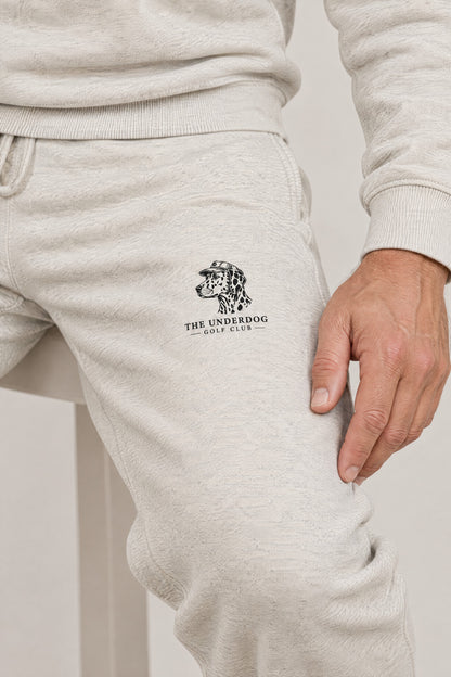 Close-up of The Underdog Golf Club Dalmatian crest on the left thigh of the Oat Gray sweatpants. Color: Oat Gray