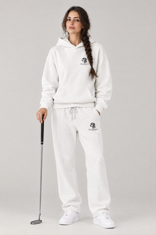Woman holding a putter in The Sweet Spot Dalmatian golf hoodie and matching Underdog Golf Club sweatpants in White, front view. Color: White