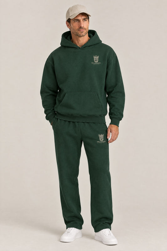 Man wearing The Marshal French Bulldog golf hoodie and matching Underdog Golf Club sweatpants in Blackish Green, front view. Color: Blackish Green