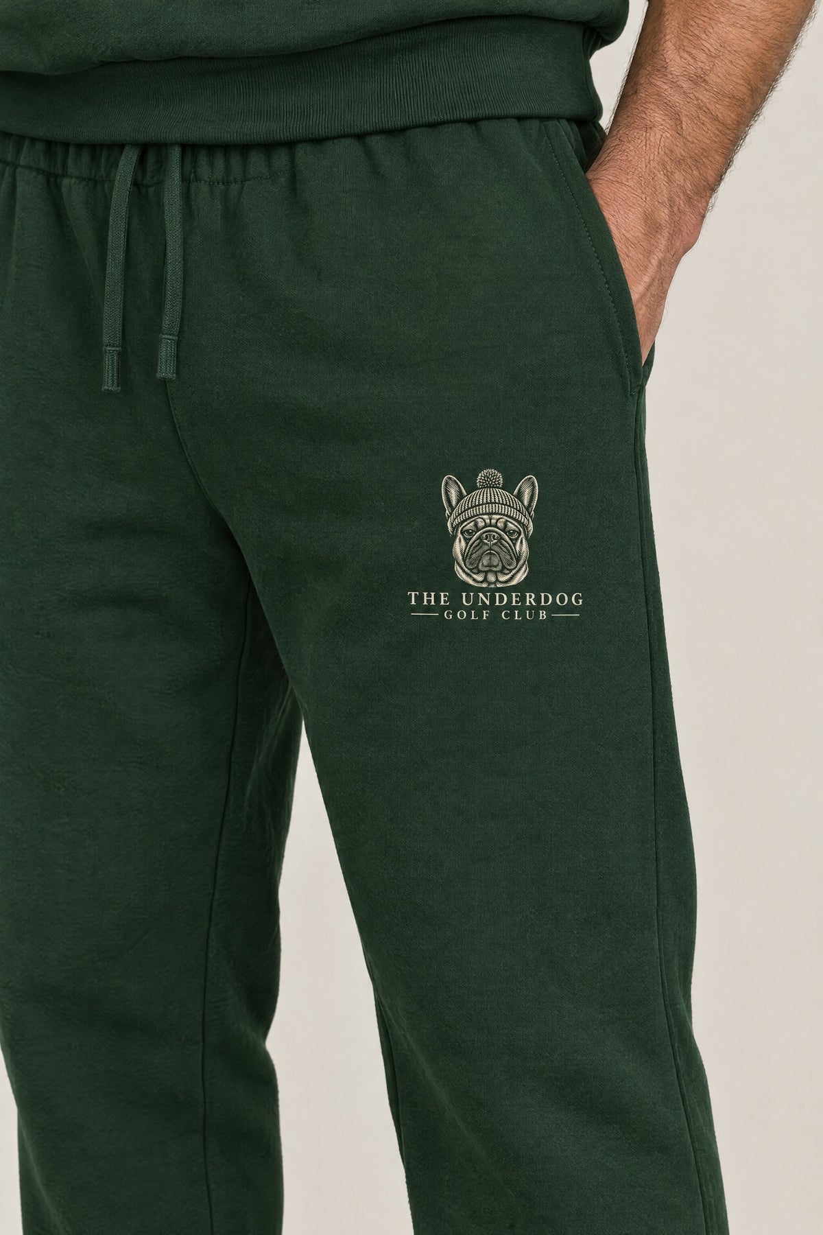 Close-up of The Underdog Golf Club French Bulldog crest on the left thigh of the Blackish Green sweatpants. Color: Blackish Green