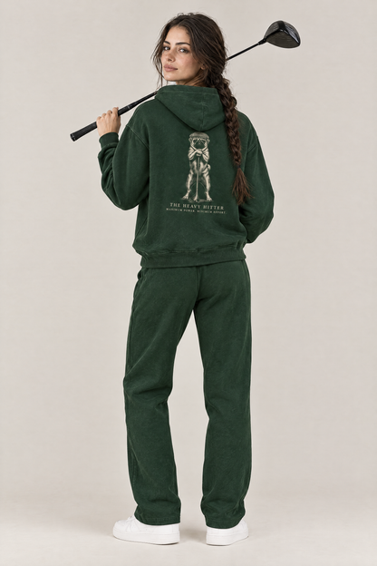 Woman with a driver over her shoulder, back view of The Heavy Hitter pug golf hoodie in Blackish Green with the large back print. Color: Blackish Green