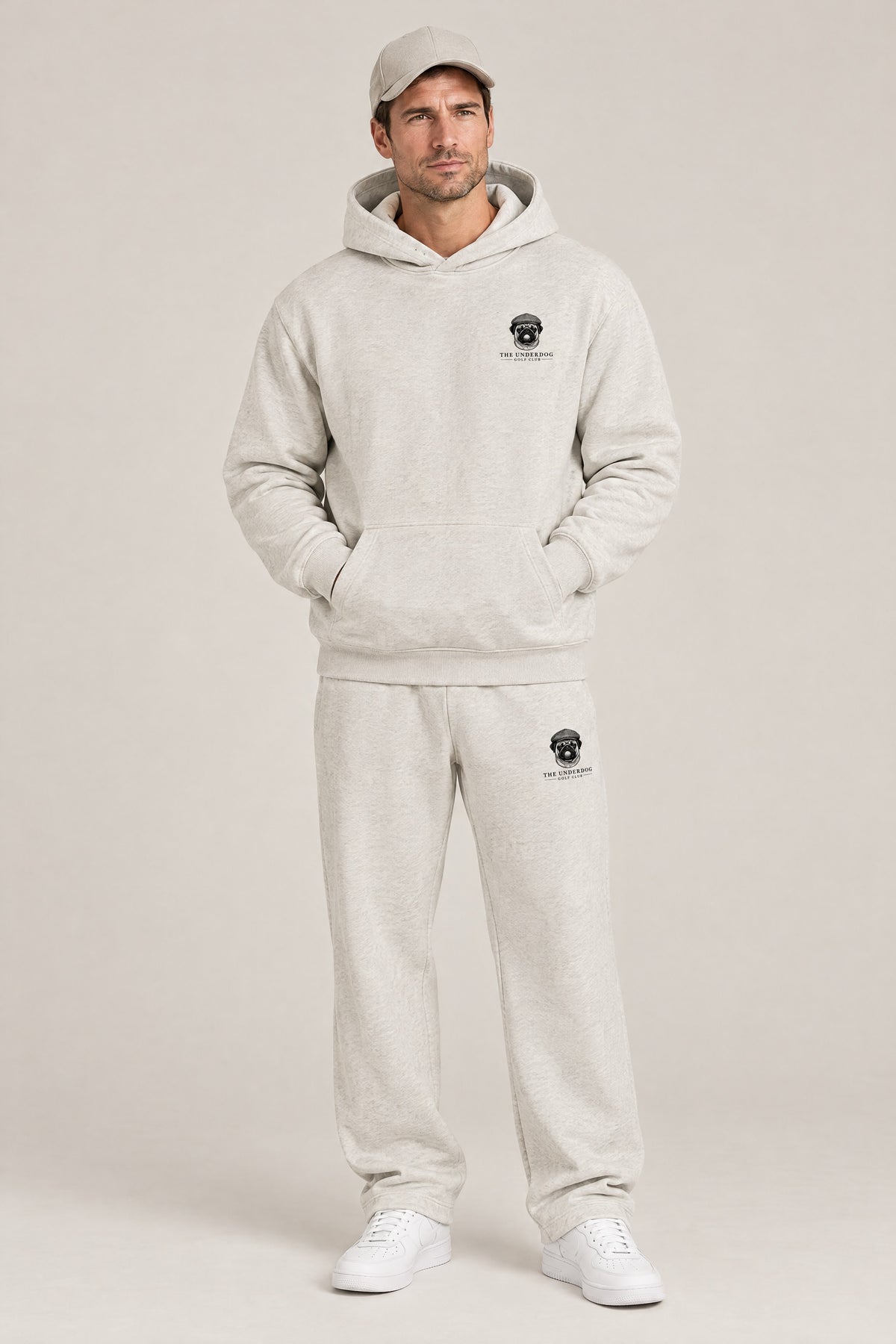 Man wearing The Heavy Hitter pug golf hoodie and matching Underdog Golf Club sweatpants in Oat Gray, front view. Color: Oat Gray
