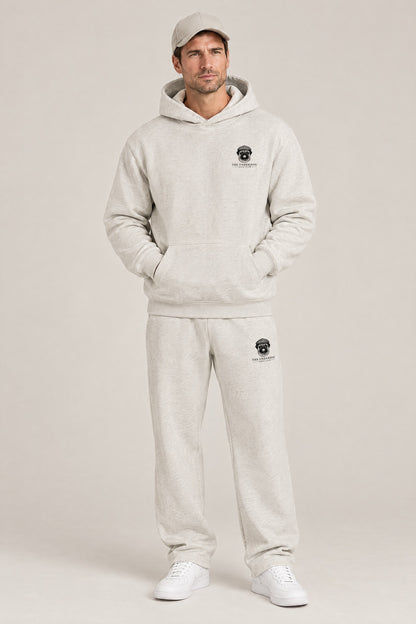 Man wearing The Heavy Hitter pug golf hoodie and matching Underdog Golf Club sweatpants in Oat Gray, front view. Color: Oat Gray