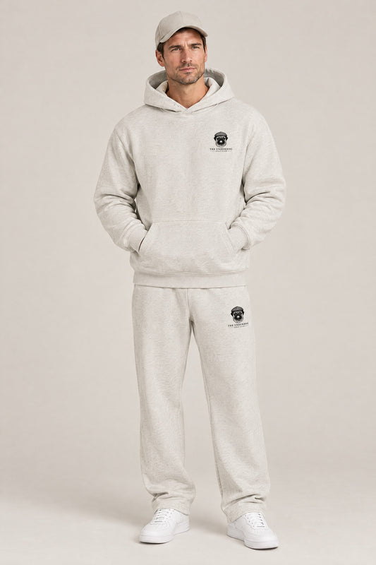 Man wearing The Heavy Hitter pug golf hoodie and matching Underdog Golf Club sweatpants in Oat Gray, front view. Color: Oat Gray