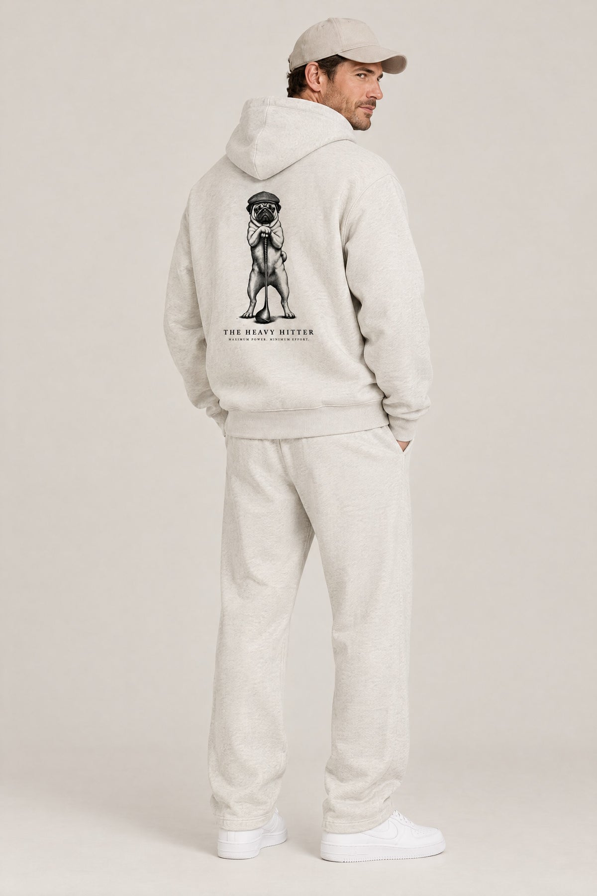 Man seen from behind in The Heavy Hitter pug golf hoodie in Oat Gray, showing the large back print. Color: Oat Gray