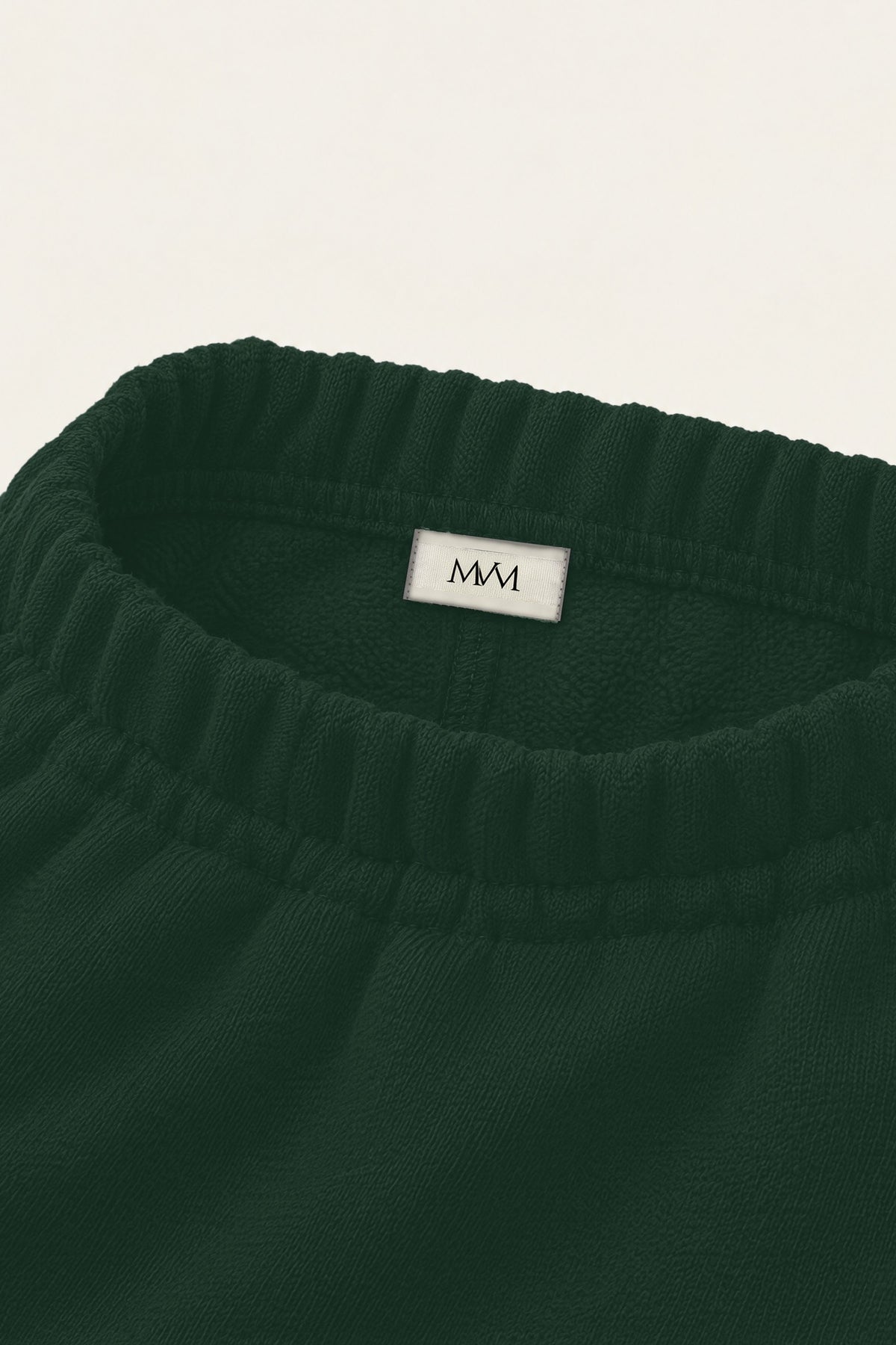 Inside of the back waistband of the blackish green Underdog Golf Club sweatpants with the MVM woven label. Color: Blackish Green