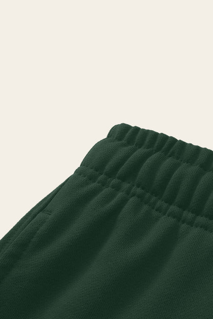 Detail of the elastic waistband and side pocket of the blackish green Underdog Golf Club sweatpants. Color: Blackish Green