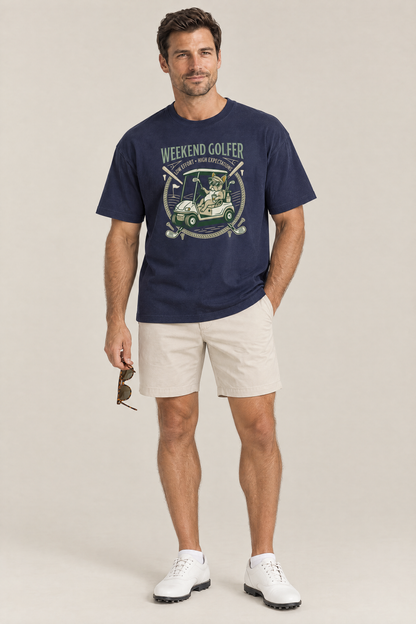 Man wearing the Weekend Golfer French Bulldog Golf Tee in navy with stone golf shorts holding sunglasses. Color: Navy