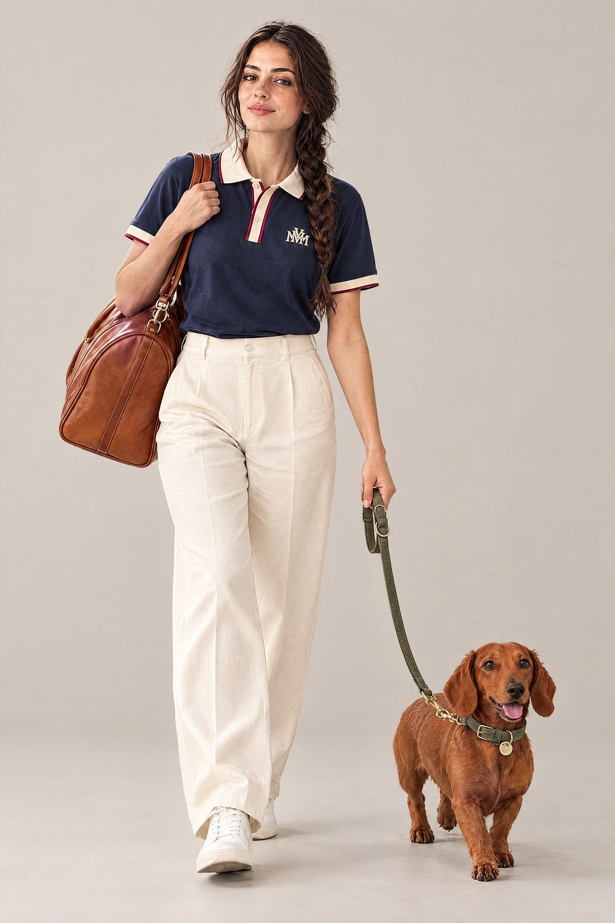 Woman in the navy Club Crest color block polo walking a red dachshund on the moss green Cloud 7 Tiergarten leash