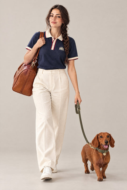 Woman in the navy Club Crest color block polo walking a red dachshund on the moss green Cloud 7 Tiergarten leash