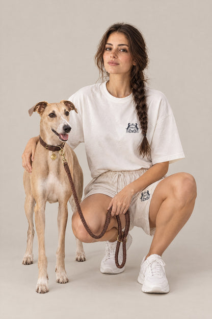 Woman in the white Club Crest tee crouching next to a whippet on the hazel Cloud 7 Ravello braided leash